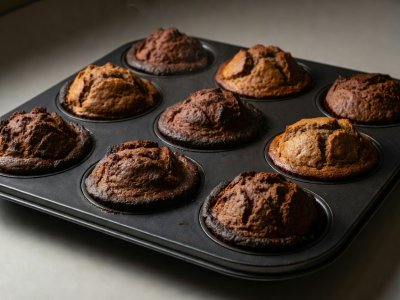 Dark charcoal nonstick muffin pan holding muffins with deeply browned, thick bottom crusts