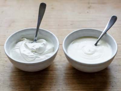Two small ceramic bowls comparing thick strained Greek yogurt beside pourable cultured buttermilk